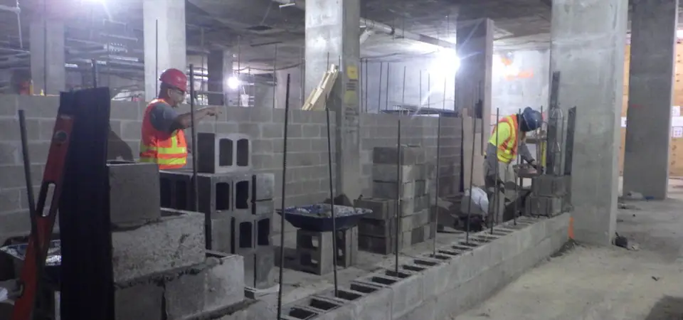 Cuadrilla levantando muros de block con varilla en el sótano de un edificio en construcción